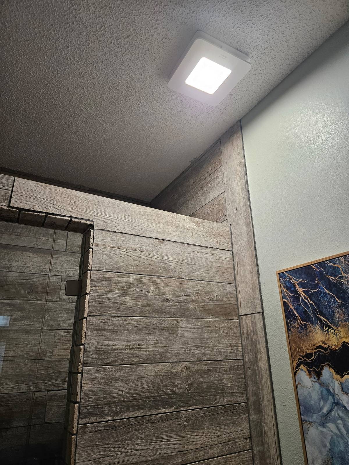 Wood-look plank tile shower surround with new ceiling vent fan and light